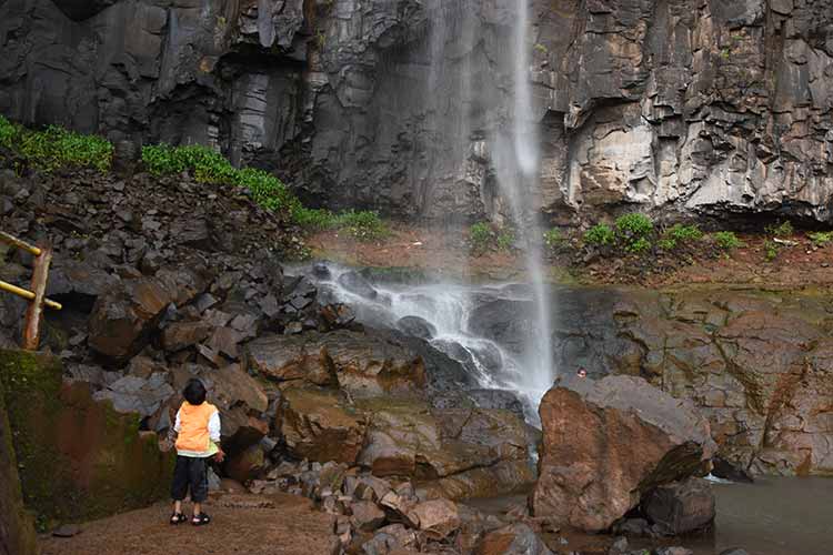 Child looking at Savarsada Waterfall